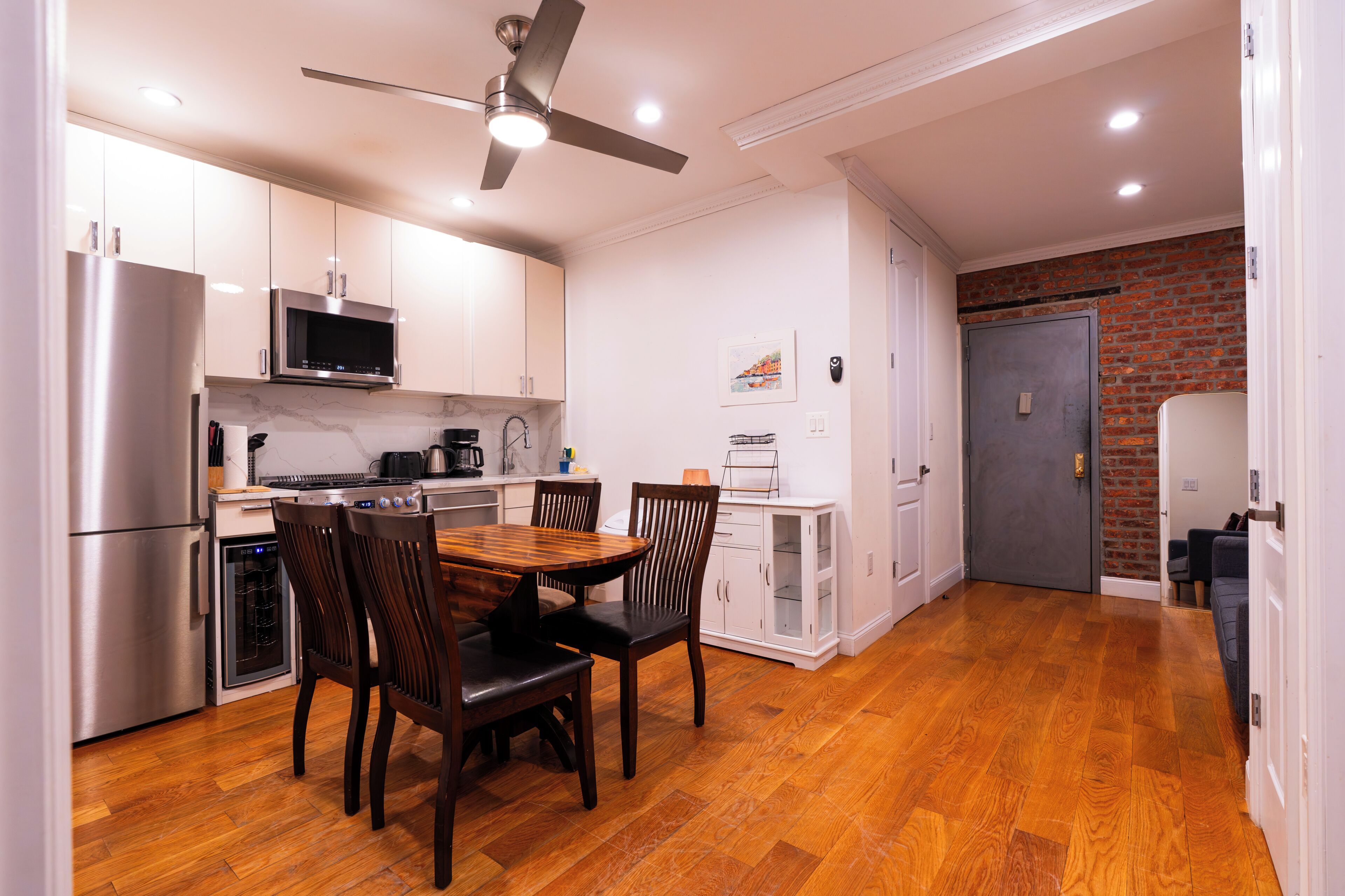 Una cocina moderna con comedor, piso de madera y ventilador de techo.