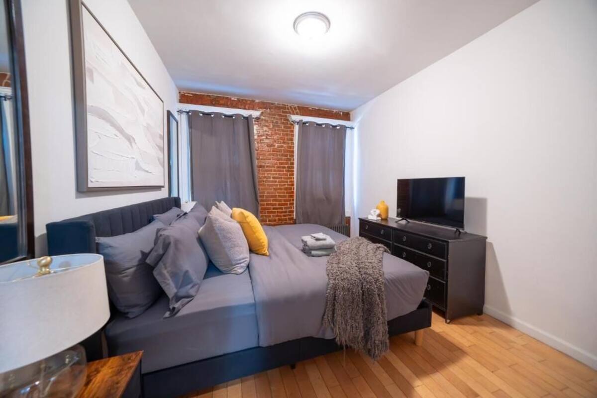 A bedroom with a bed, a TV, a dresser, and a lamp.