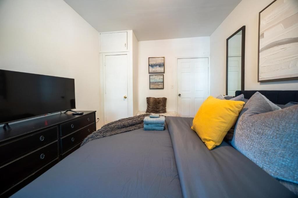 Un dormitorio con cama, televisor, cómoda y puerta.