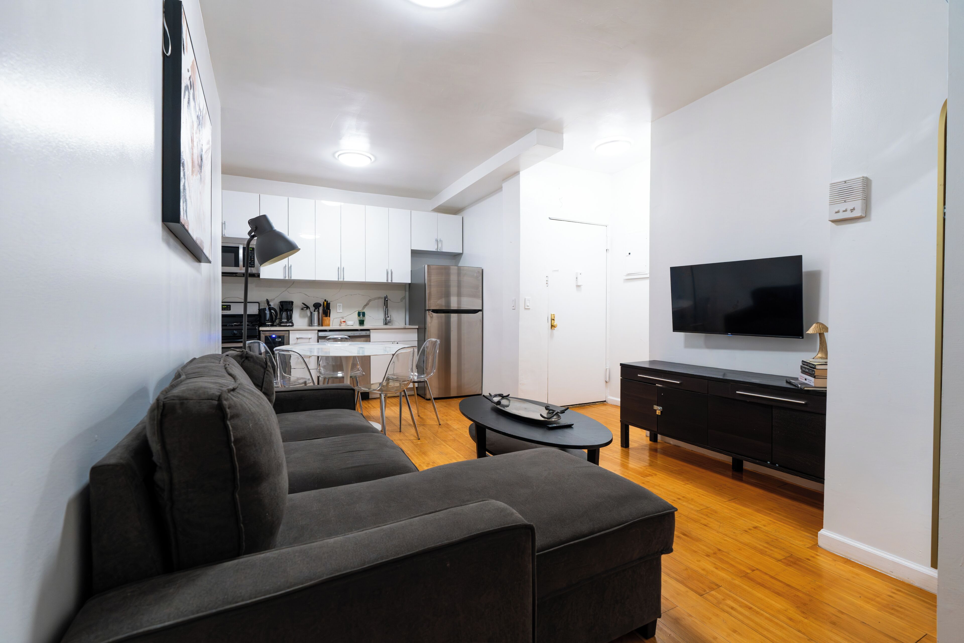 A modern living room with a sofa, a TV, and a dining area with chairs.