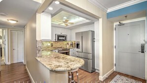 A modern kitchen with granite countertops, stainless steel appliances, and a ceiling fan. - 2 Bedroom beach/pool view,37ft balcony, boat slip,6 month rental only, May-Oct. (Marco Island)