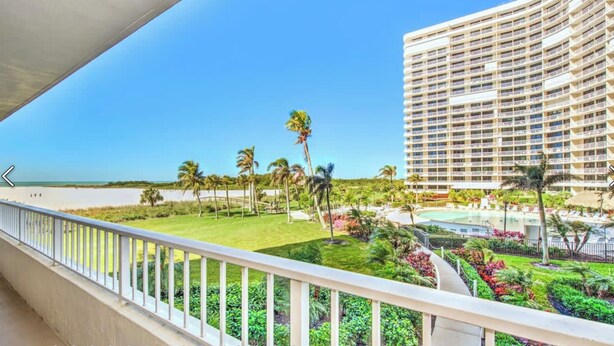 A hotel with a pool, palm trees, and a beach view. - 2 Bedroom beach/pool view,37ft balcony, boat slip,6 month rental only, May-Oct. (Marco Island)