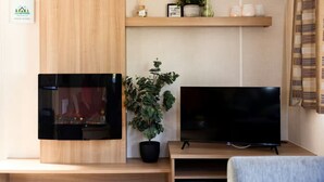 Ett modernt vardagsrum med en öppen spis, en platt-TV och en krukväxt.