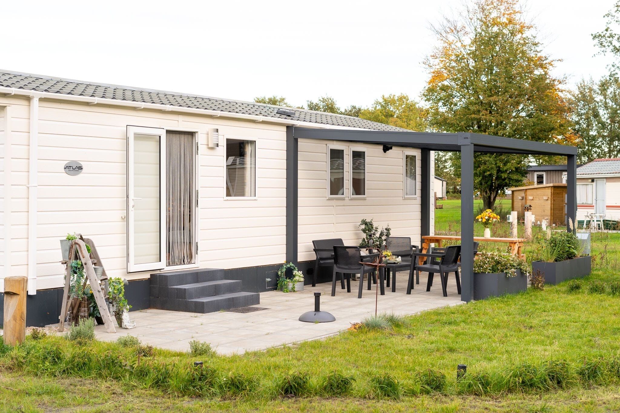 Ein Wohnmobil mit Terrasse, Sitzgelegenheit im Freien und einem Garten.