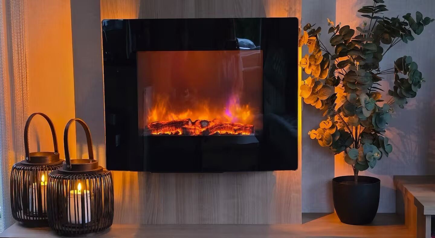 Ein Kamin mit sichtbarem Feuer, zwei Kerzenleuchter und ein Blumentopf.