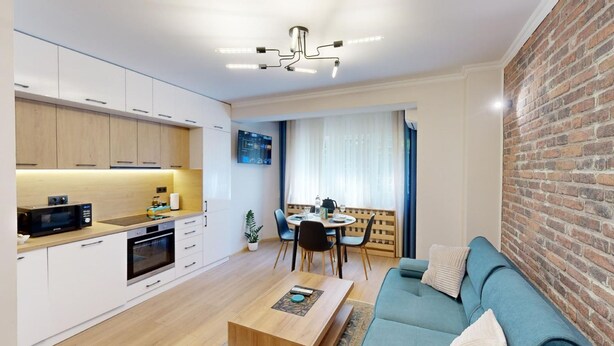 A modern kitchen with white cabinets, a microwave, and a dining area with a table and chairs. - Apartment TOP center Sofia, 5 Corners (Sofia)