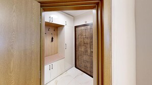 A hallway with a wooden door, white cabinets, and a bench. - Apartment TOP center Sofia, 5 Corners (Sofia)