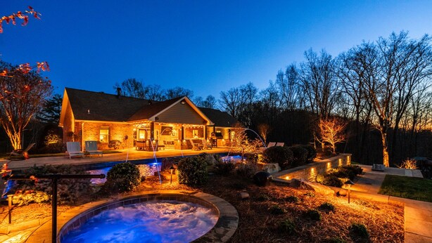 A house with a swimming pool, outdoor seating, and a hot tub.