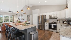 A modern kitchen with stainless steel appliances, a large island with bar stools, and pendant lighting.