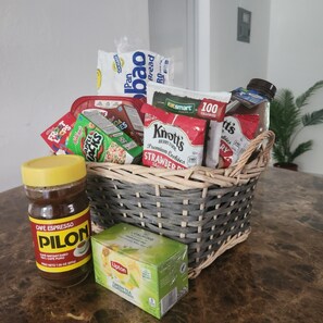 Ein Korb mit verschiedenen Lebensmitteln, darunter Snacks, eine Kaffeeglas und eine Teedose.
