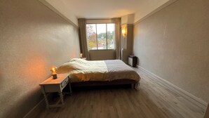 A bedroom with a bed, bedside lamp, and a window with curtains.
