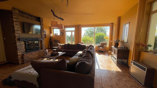 A living room with a fireplace, a sofa, a TV, and a large window.