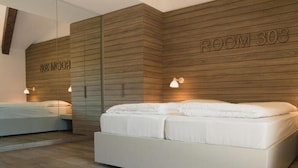 Een moderne slaapkamer met een groot bed, een kleiner bed, houten paneelwanden en een bordje met 'ROOM 308'.