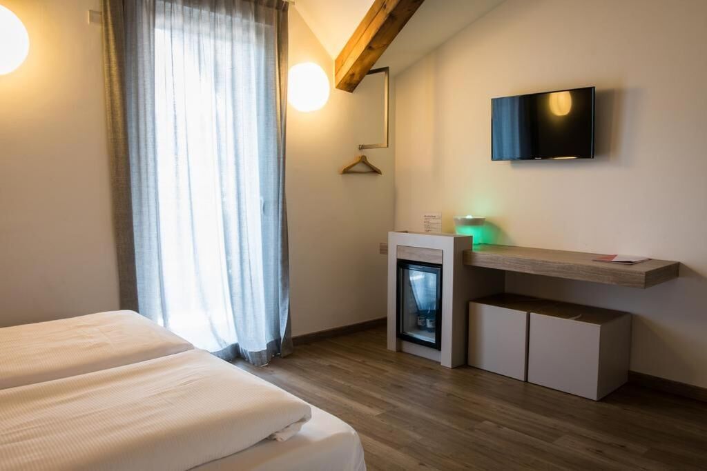 Una camera d'albergo con un letto, una TV a parete, un piccolo camino e un soffitto in legno.