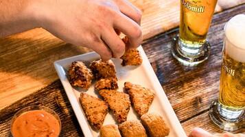 Une table en bois sur laquelle se trouvent une assiette de nourriture frite, un verre de bière et un petit bol de sauce.