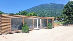 Een modern gebouw met grote ramen, een houten gevel en een parkeerplaats.