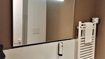 A bathroom with a white sink, a mirror, a towel rack, and a toilet.