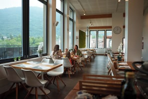 A dining area with tables, chairs, and a view of a mountainous landscape.