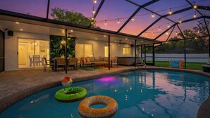 An indoor pool area with a covered patio, seating, and a view of the outdoors. -  The Mimosa House • Heated Salt Water Pool + Spa • Minutes to Siesta Key (Sarasota)