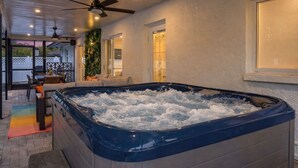 A hot tub in a room with a ceiling fan, a window with a view, and a door. -  The Mimosa House • Heated Salt Water Pool + Spa • Minutes to Siesta Key (Sarasota)