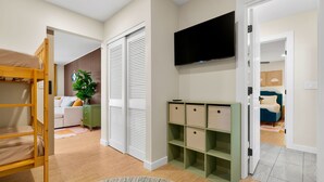 A room with a bunk bed, a television, a green storage unit, and a white wardrobe. -  The Mimosa House • Heated Salt Water Pool + Spa • Minutes to Siesta Key (Sarasota)