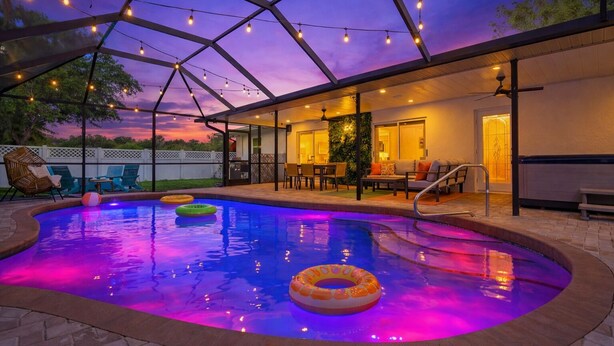 A covered outdoor pool area with seating and string lights. -  The Mimosa House • Heated Salt Water Pool + Spa • Minutes to Siesta Key (Sarasota)
