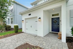 Ein Wohnhaus mit weißer Fassade, einer blauen Haustür und einer Garage.