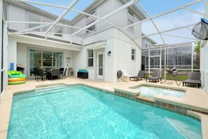 Ein Schwimmbecken mit Liegestühlen und einer überdachten Terrasse.