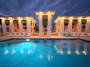 Ein Pool mit Liegestühlen und einem überdachten Bereich mit Säulen und Treppe.