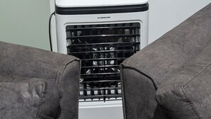 Ein Zimmer mit Klimaanlage, grauem Sofa und Holzboden.