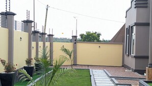 Ein Innenhof mit einem gepflasterten Weg, einer kleinen Rasenfläche und einer Mauer mit einem Tor.