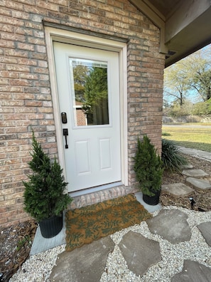 A brick house with a white door, two potted evergreen trees, and a stone pathway leading to the door. - Peaceful Boutique Suite • Private Entry • Near Beach & Downtown (Pensacola)