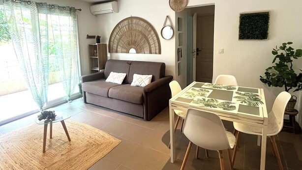 A living room with a sofa, a dining table with chairs, a small rug, and a potted plant. - Cosy Corner (Villeneuve-Loubet)