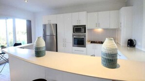 Une cuisine moderne avec des armoires blanches, des appareils en acier inoxydable et un grand îlot central.
