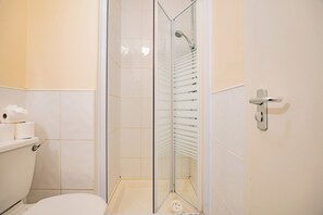 Une salle de bain avec une douche à parois de verre, des toilettes et un porte-serviettes.