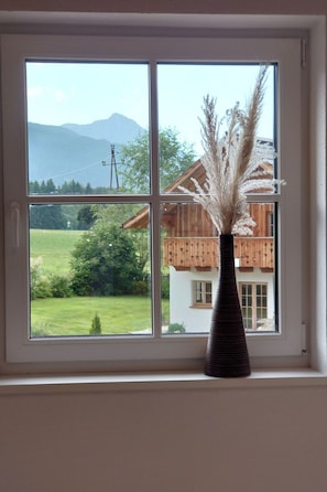 Ein Fenster mit Blick auf ein Haus und Berge.