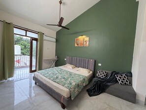 Ein Schlafzimmer mit Bett, einer Sitzbank, einem Deckenventilator, einem Fenster mit Vorhängen und einer wandmontierten Klimaanlage.