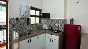 Uma cozinha com armários brancos, micro-ondas, geladeira Samsung, dispenser de água e painel de fundo padronizado.