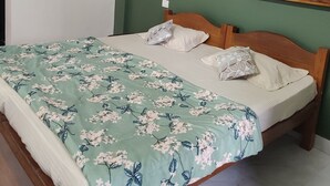 Um quarto com uma cama, um ventilador de teto e três quadros na parede.