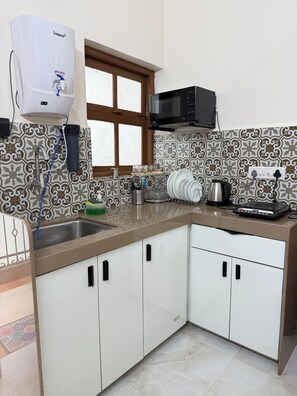A kitchen with a sink, a microwave, and a water dispenser. - Casa Bella-2BHK apartment near Candolim beach (Candolim)