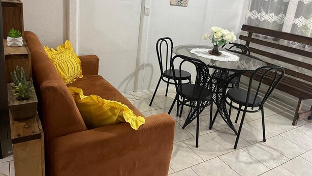 Un soggiorno con un divano marrone, un tavolo da pranzo rotondo con sedie, una panca e decorazioni a parete.