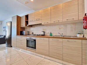 Eine moderne Küche mit Holzausstattung, Backofen, Mikrowelle und Gasherd.