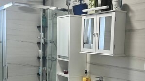 Une salle de bain moderne avec une douche à parois de verre, un lavabo avec un miroir et un lave-linge.