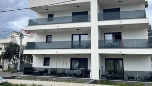 Un immeuble résidentiel à plusieurs étages, doté de balcons, d’un toit plat et surplombant un ciel dégagé.