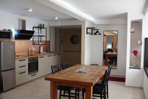 A modern kitchen with stainless steel appliances, a wooden dining table, and a dining area with chairs.