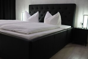A bed with a tufted headboard, white bedding, and two bedside tables with lamps.
