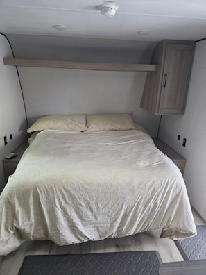 A bed with a headboard, a bedside table, and a wardrobe.