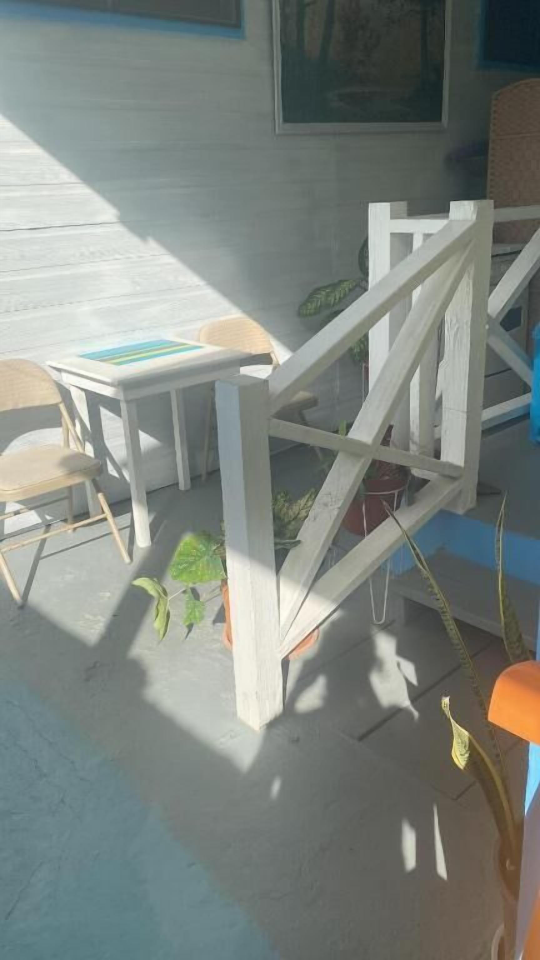A room with a white table, a chair, and a white railing.
