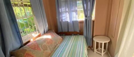 A room with a bed, a small round table, and a window with curtains.