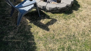 Ein Garten mit Feuerschale und Adirondack-Stühlen.